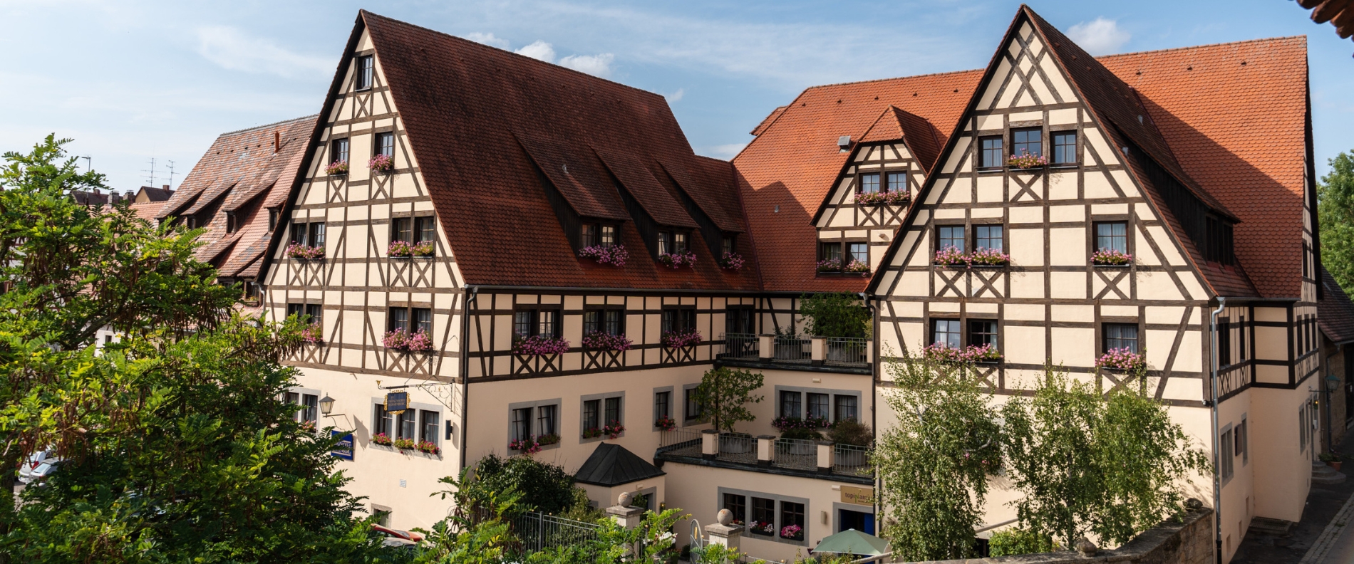 Außenansicht des Prinzhotel Rothenburg im historischen Fachwerkstil mit blumengeschmückten Fenstern.