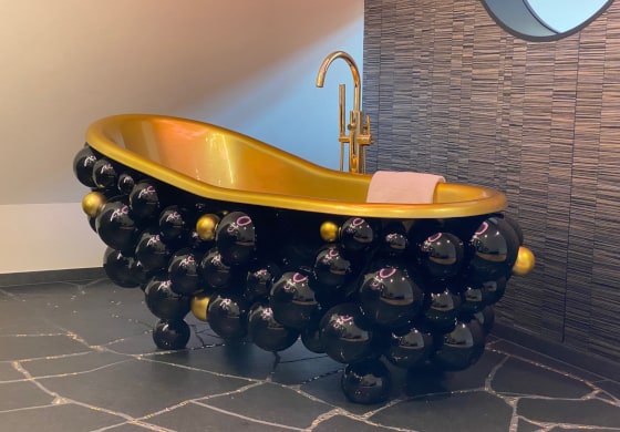 Goldene Badewanne mit schwarzen Kugeln