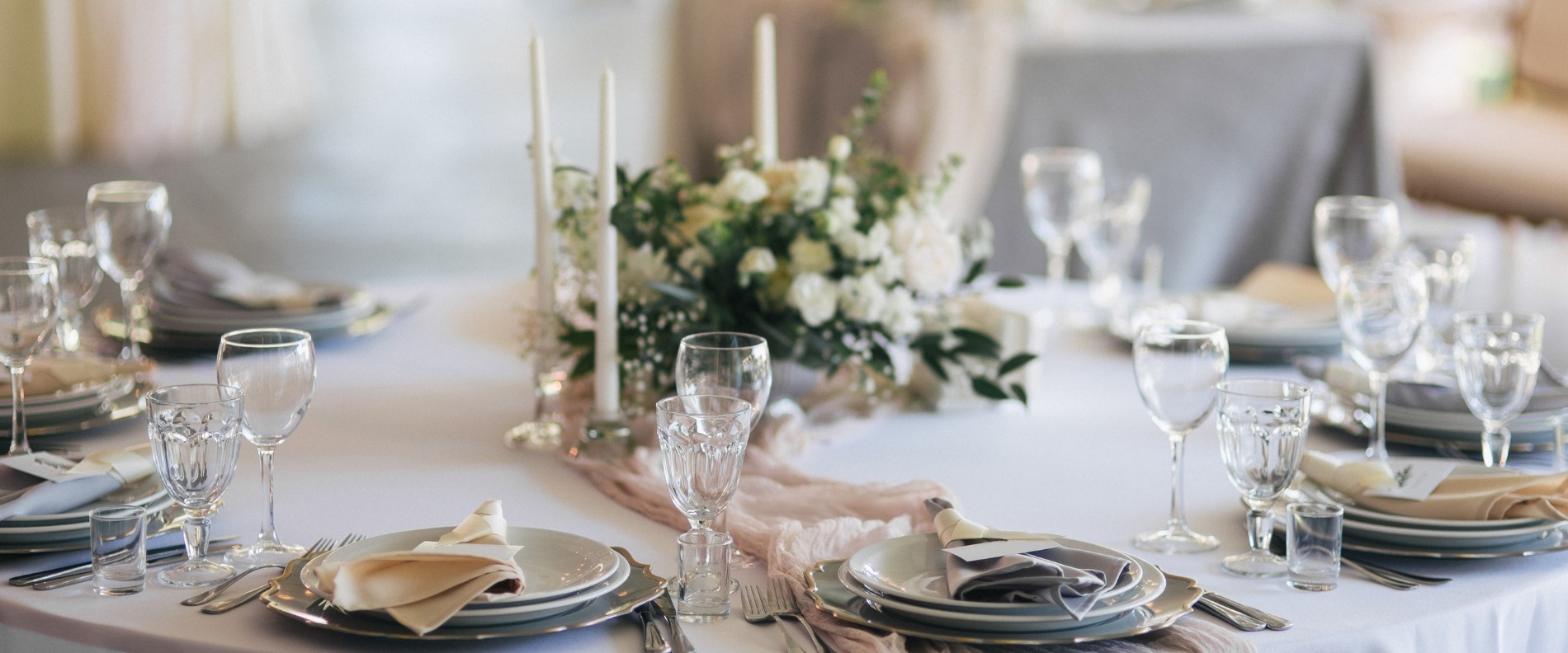 Elegant gedeckter Tisch mit weißer Tischdecke, Kristallgläsern, gefalteten Servietten und einem Blumenarrangement