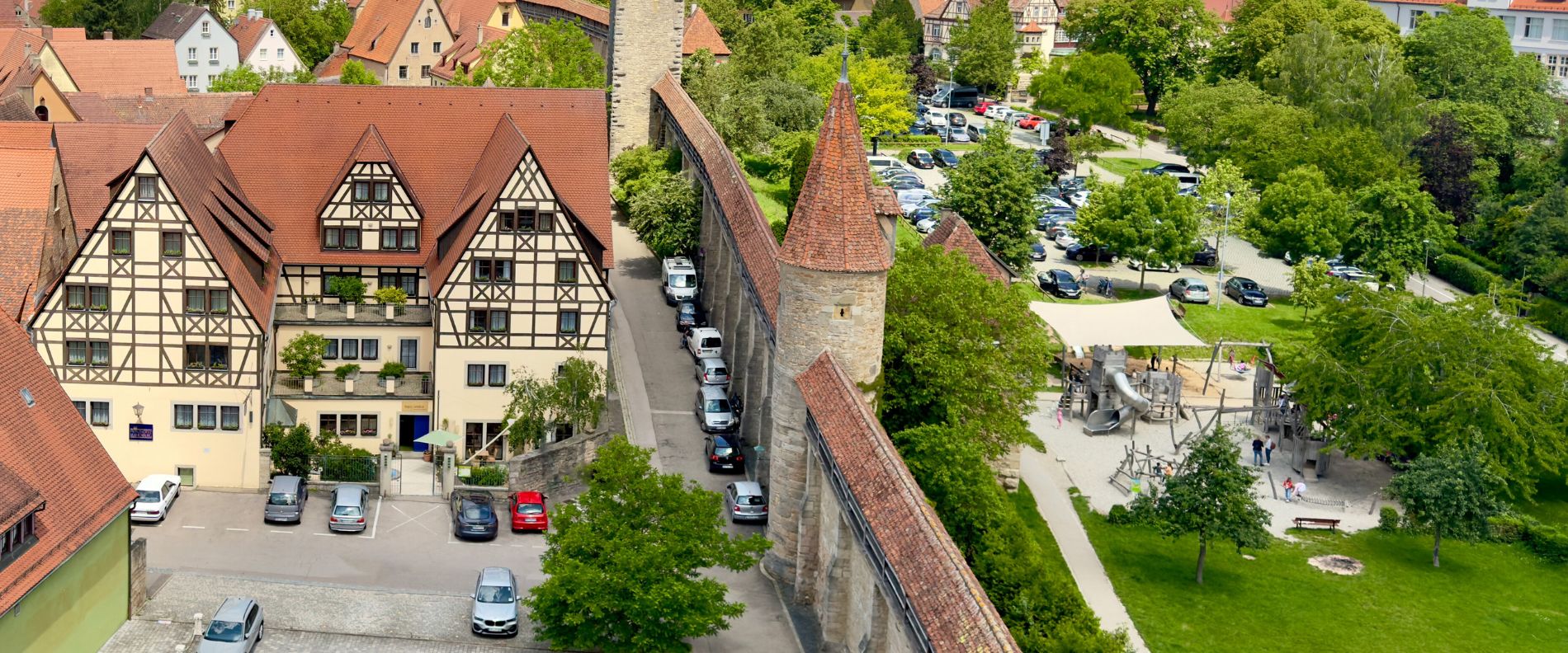 Luftaufnahme von Rothenburg ob der Tauber: Fachwerkh&auml;user, mittelalterliche Stadtmauer, Spielplatz und gr&uuml;ne Umgebung.