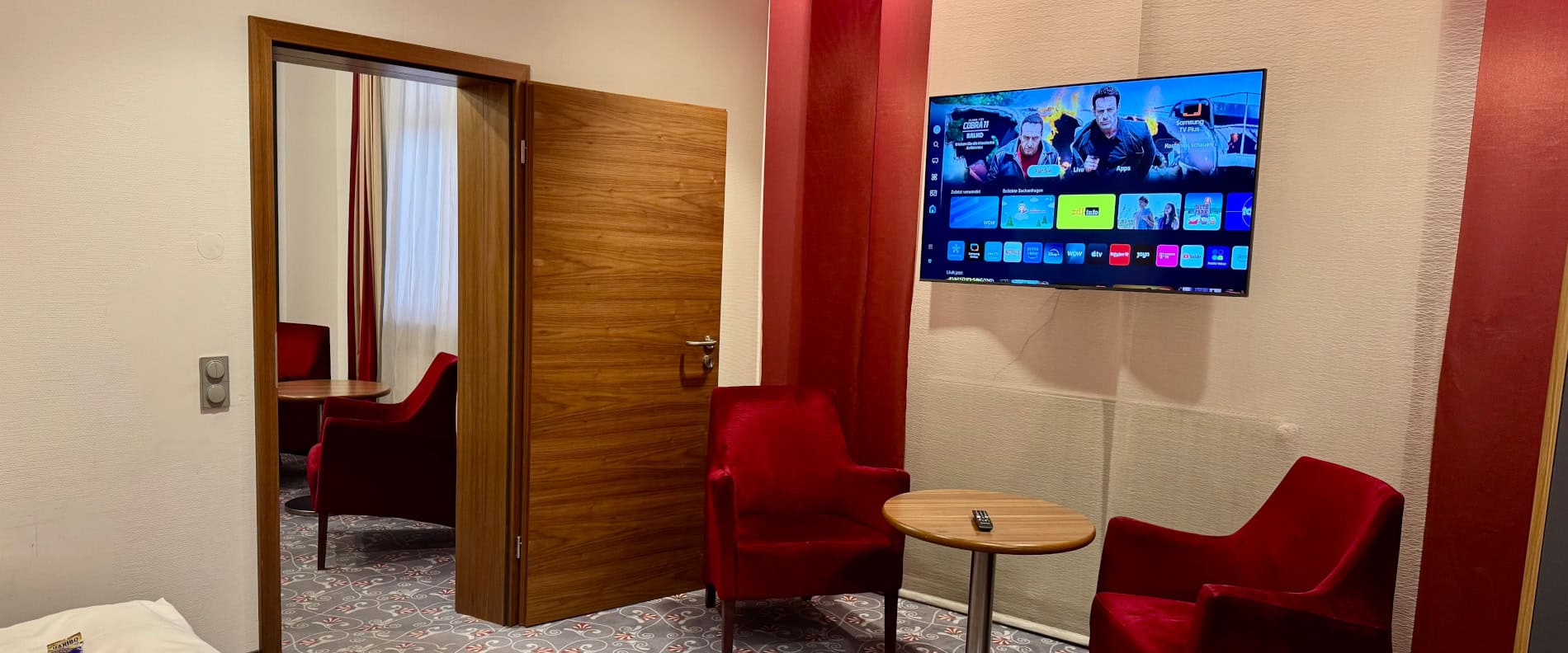 Gem&uuml;tliche Sitzecke mit roten Sesseln und Fernseher im Familienzimmer des Prinzhotel Rothenburg