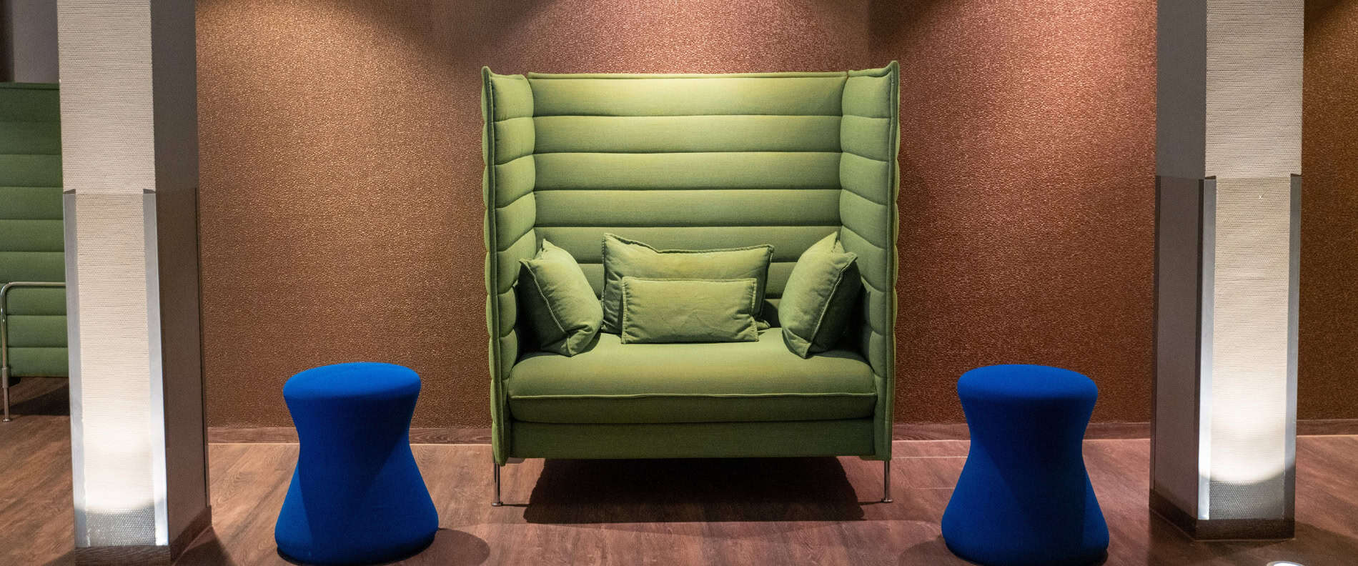 Moderner Lounge-Bereich im Prinzhotel Rothenburg – grünes Sofa mit blauen Hockern in stilvollem Ambiente