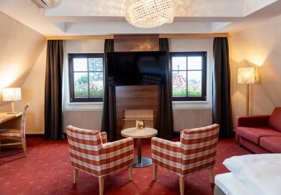 Wellness Suite im Prinzhotel Rothenburg – gemütlicher Wohnbereich mit Sesseln, Sofa und großem TV