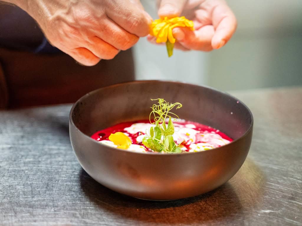 Freshly prepared gourmet soup being finished and garnished at the kitchen pass before serving.
